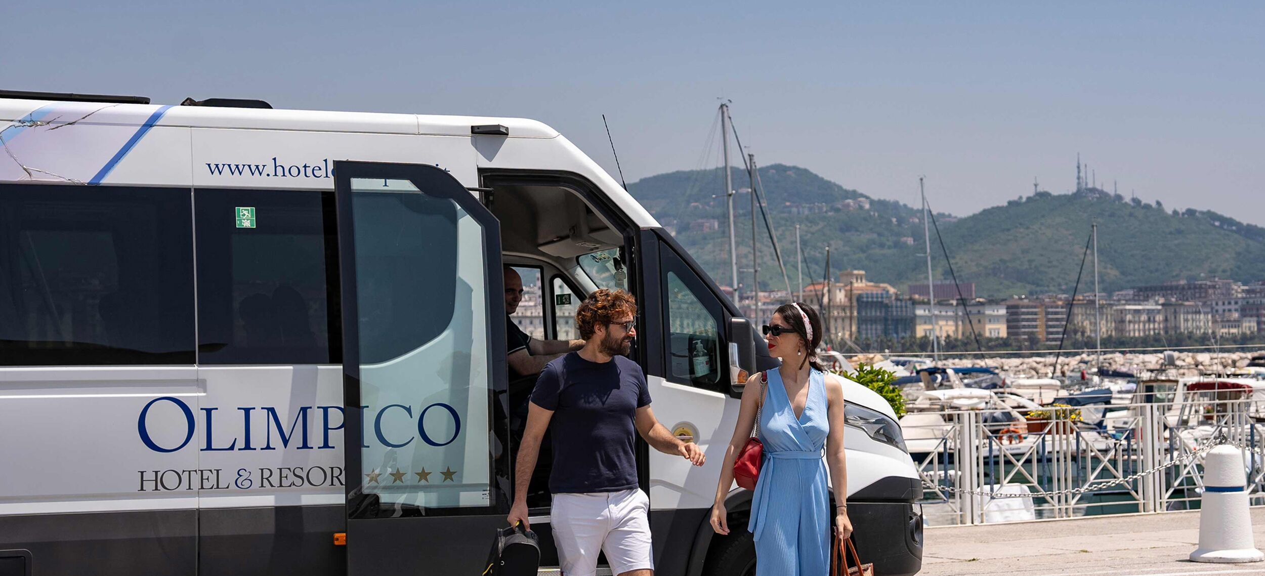 Una camioneta blanca con la leyenda "OLIMPICO HOTEL & RESORT" y una dirección web.