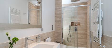 Un baño moderno con cabina de ducha de vidrio, un lavabo grande y un espejo.