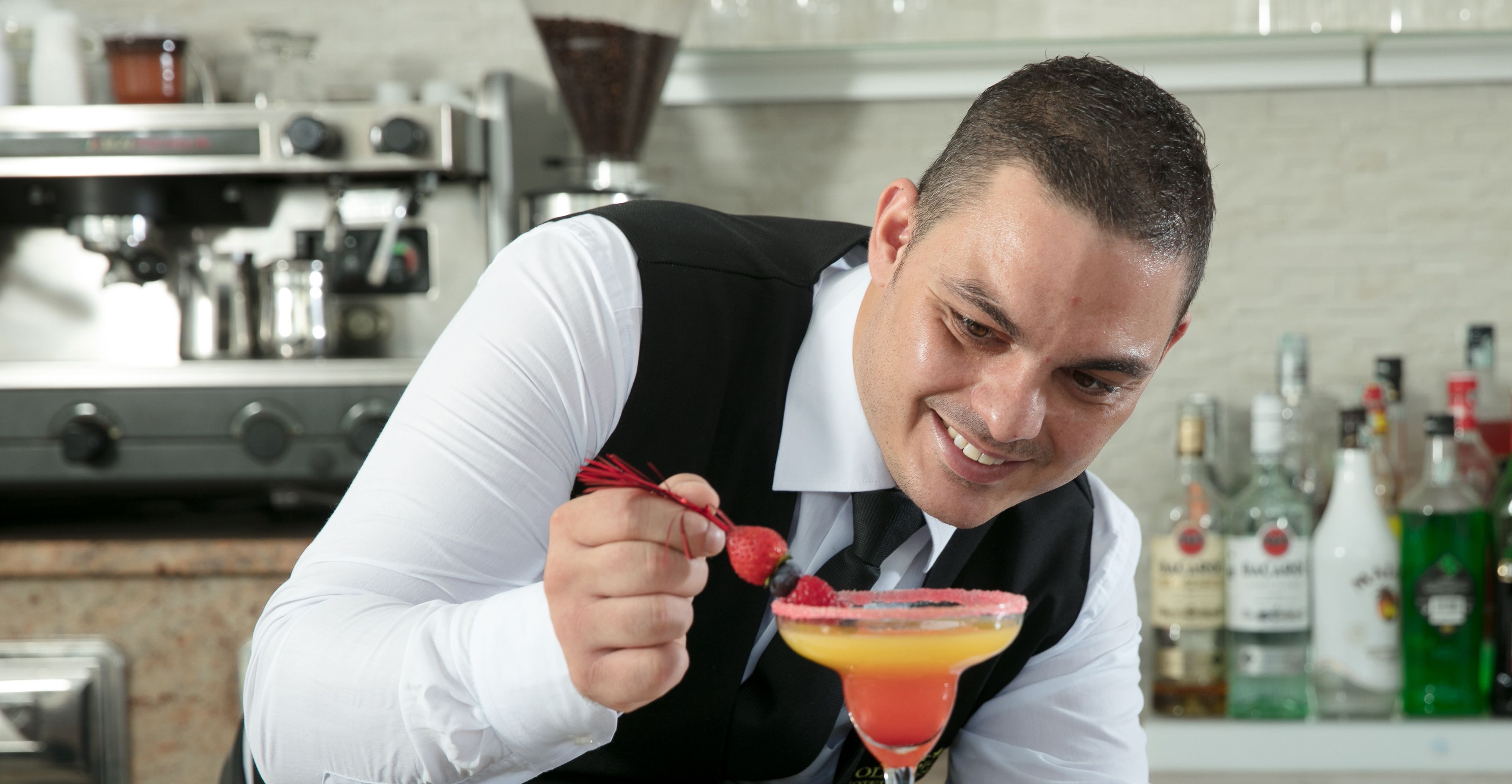 Un bar con una persona sosteniendo un cóctel adornado con fresas.