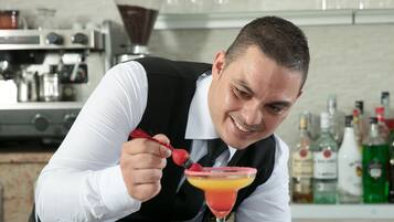 Un bar con una persona sosteniendo un cóctel adornado con fresas.