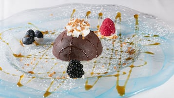 A dessert with chocolate, berries, and caramel sauce on a clear glass plate.