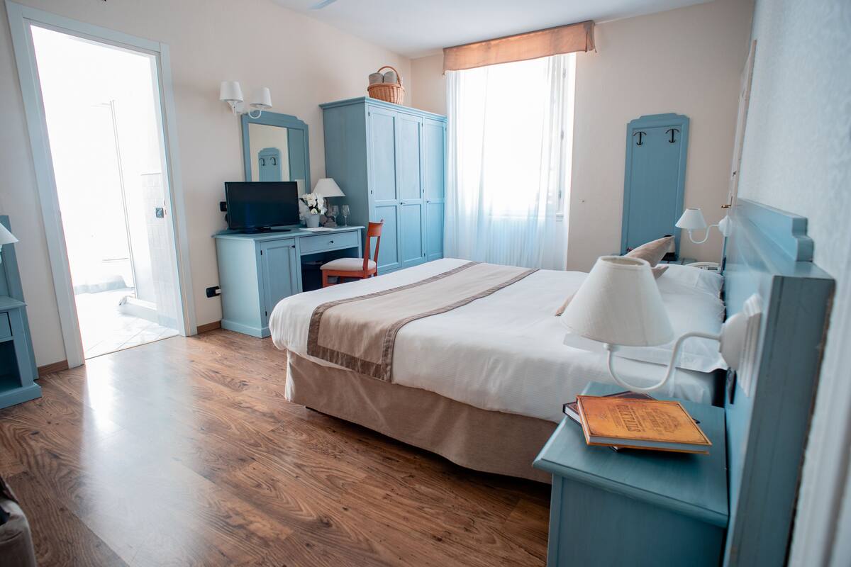 A bedroom with a bed, a desk, a chair, a television, and a wardrobe.