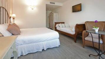 Una camera d'albergo con un letto, una sedia, un tavolino e una TV a parete.