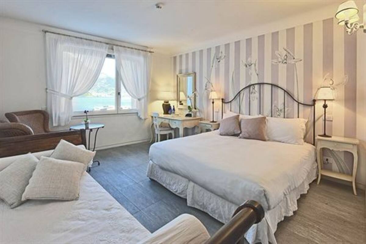 A bedroom with a bed, a desk, and a chair. There is a window with curtains.