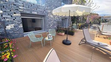 Une terrasse en bois avec des sièges d’extérieur, un mur en pierre et une vue sur l’eau.