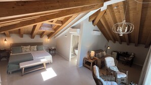 A cozy attic bedroom with a large bed, a small table, and a wicker chair. - Hotel Villa Aurora (Lezzeno)