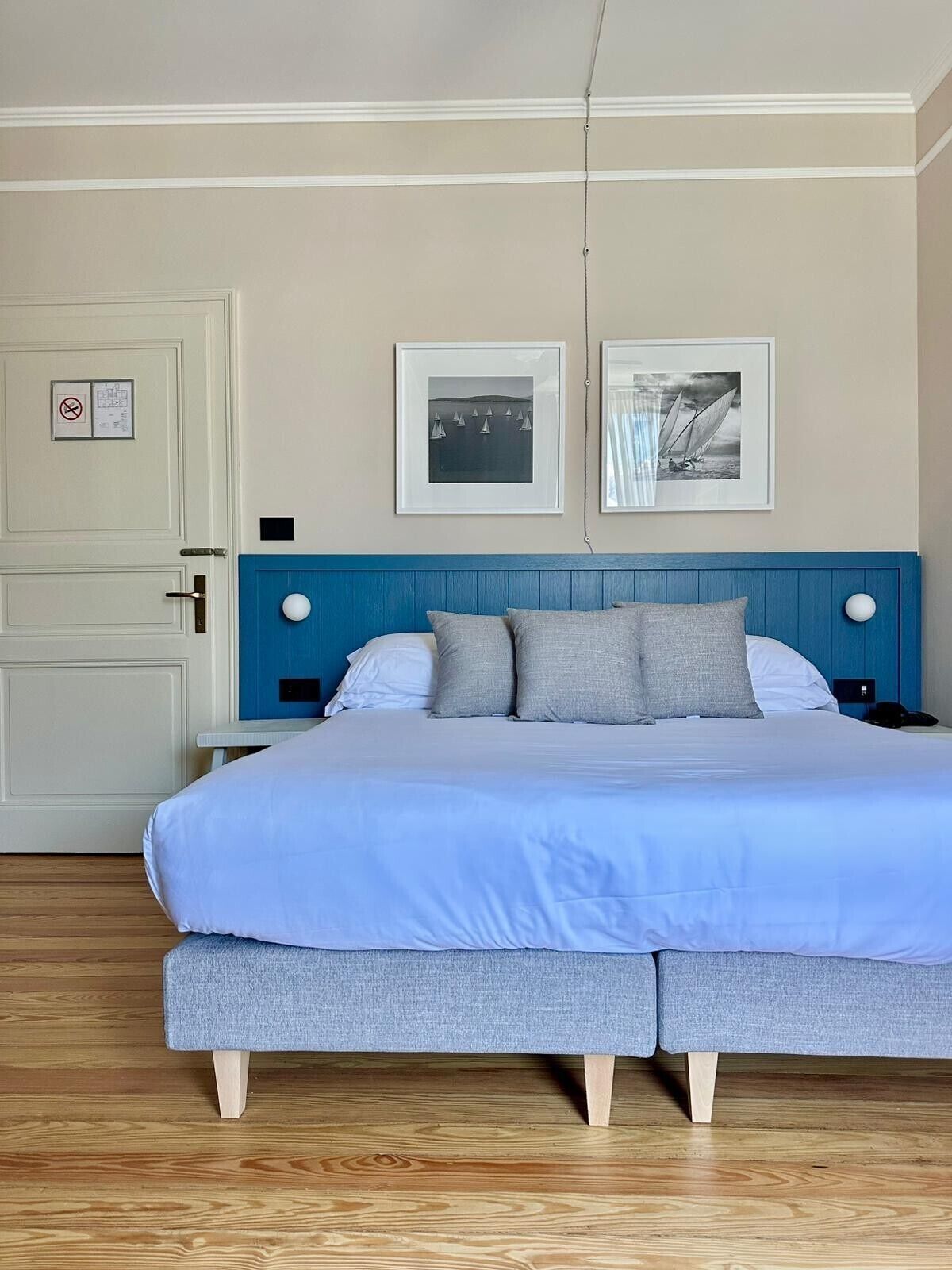 A bedroom with a bed, a door with a sign, and two framed pictures on the wall.