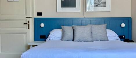 A bedroom with a bed, a door with a sign, and two framed pictures on the wall.