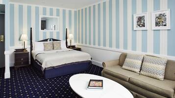 Une chambre d’hôtel avec un lit, un canapé, une table de chevet, une lampe et un livre posé sur une table.
