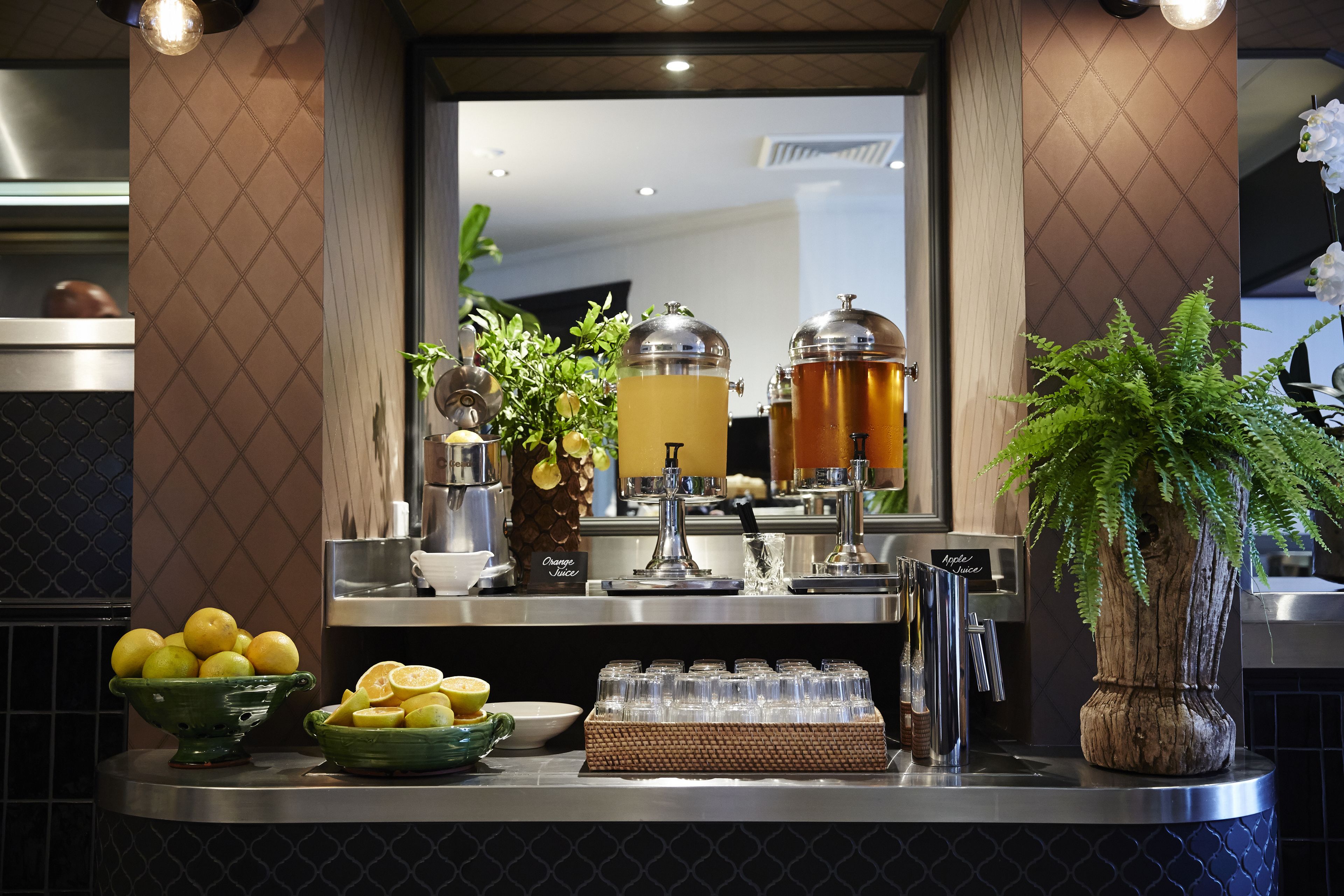 Ein Buffet mit verschiedenen Früchten, einer Getränkestation und einer Zierpflanze.