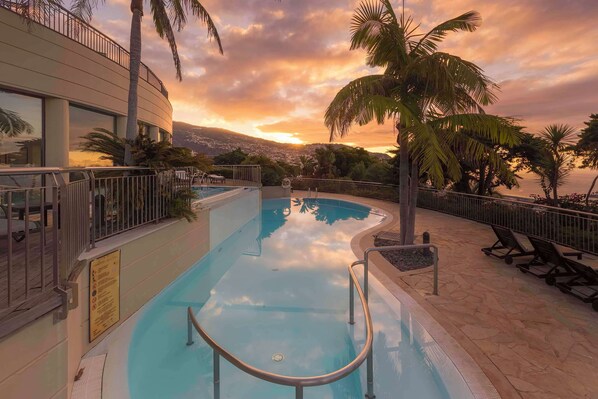 Una piscina cubierta, una piscina al aire libre, sombrillas, tumbonas