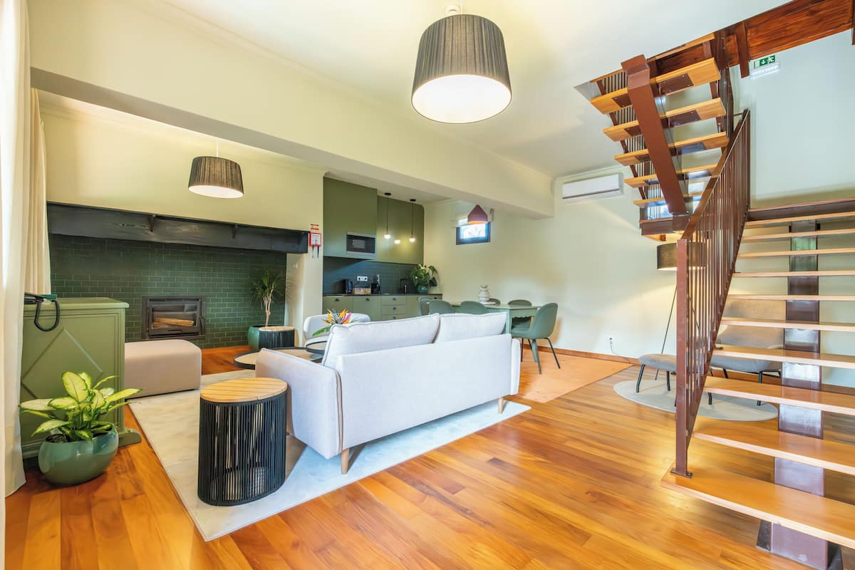 A modern living room with a sofa, dining table, and staircase.