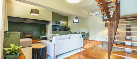 A modern living room with a sofa, dining table, and staircase.