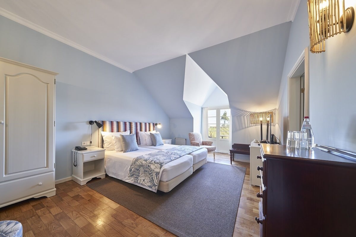 A bedroom with a large bed, bedside tables, a dresser, and a mirror.