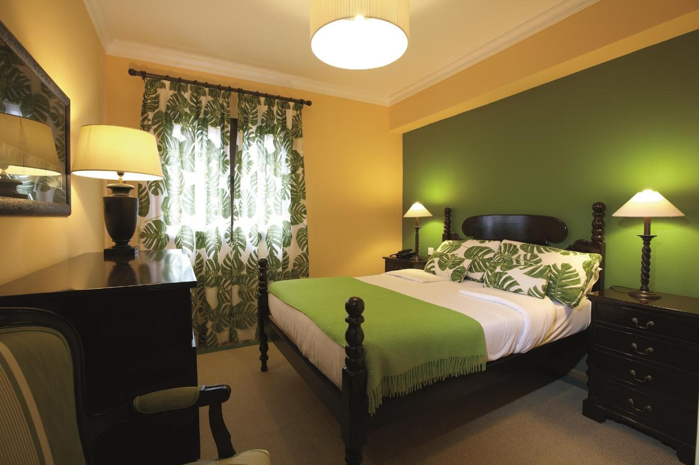A bedroom with a bed, bedside tables, a desk, and a chair.