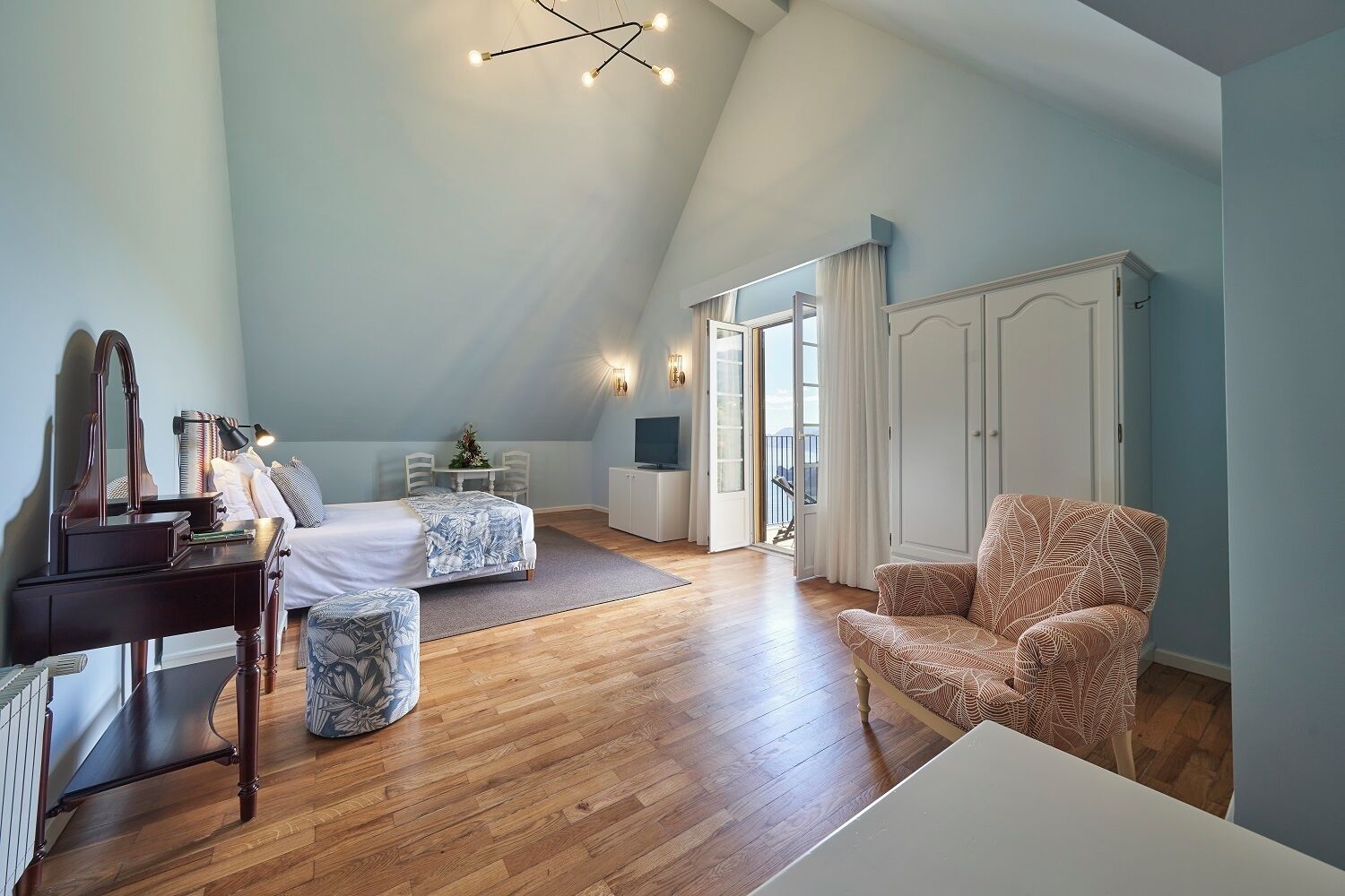 A bedroom with a bed, a desk, a chair, a television, and a wardrobe.