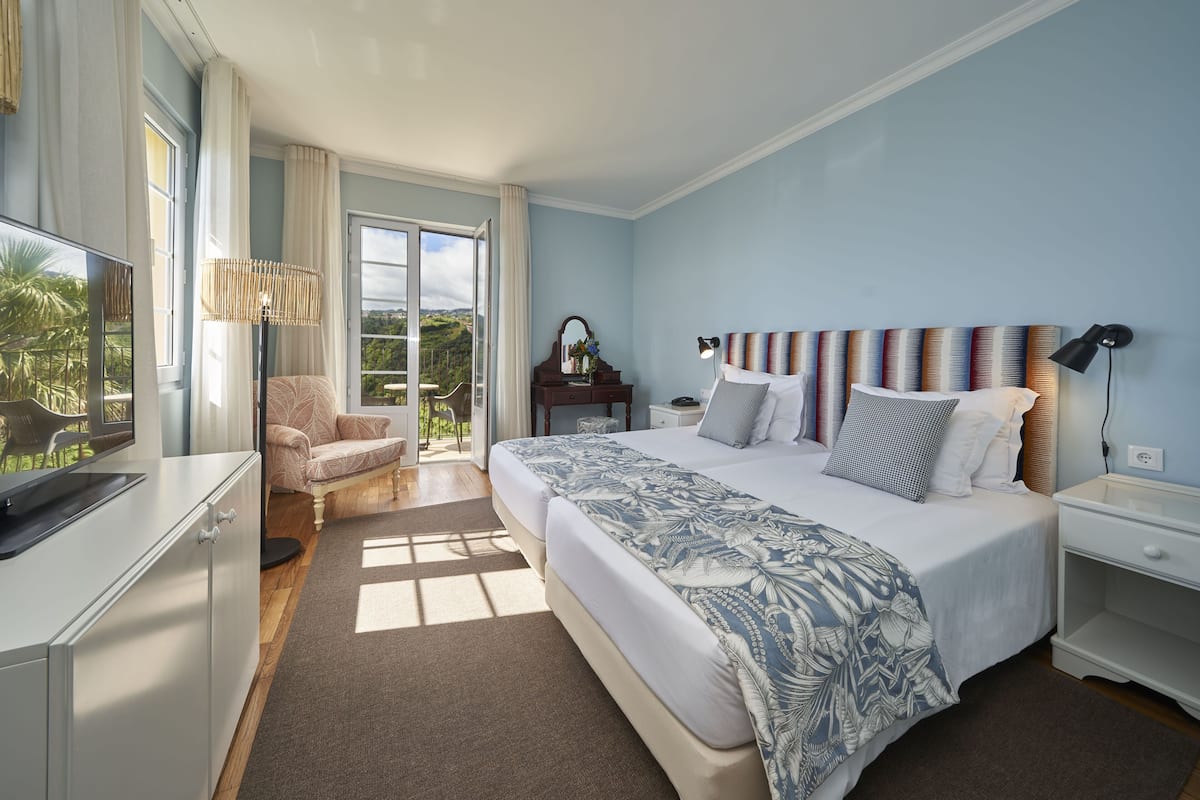 A bedroom with a large bed, a desk, a chair, and a TV.
