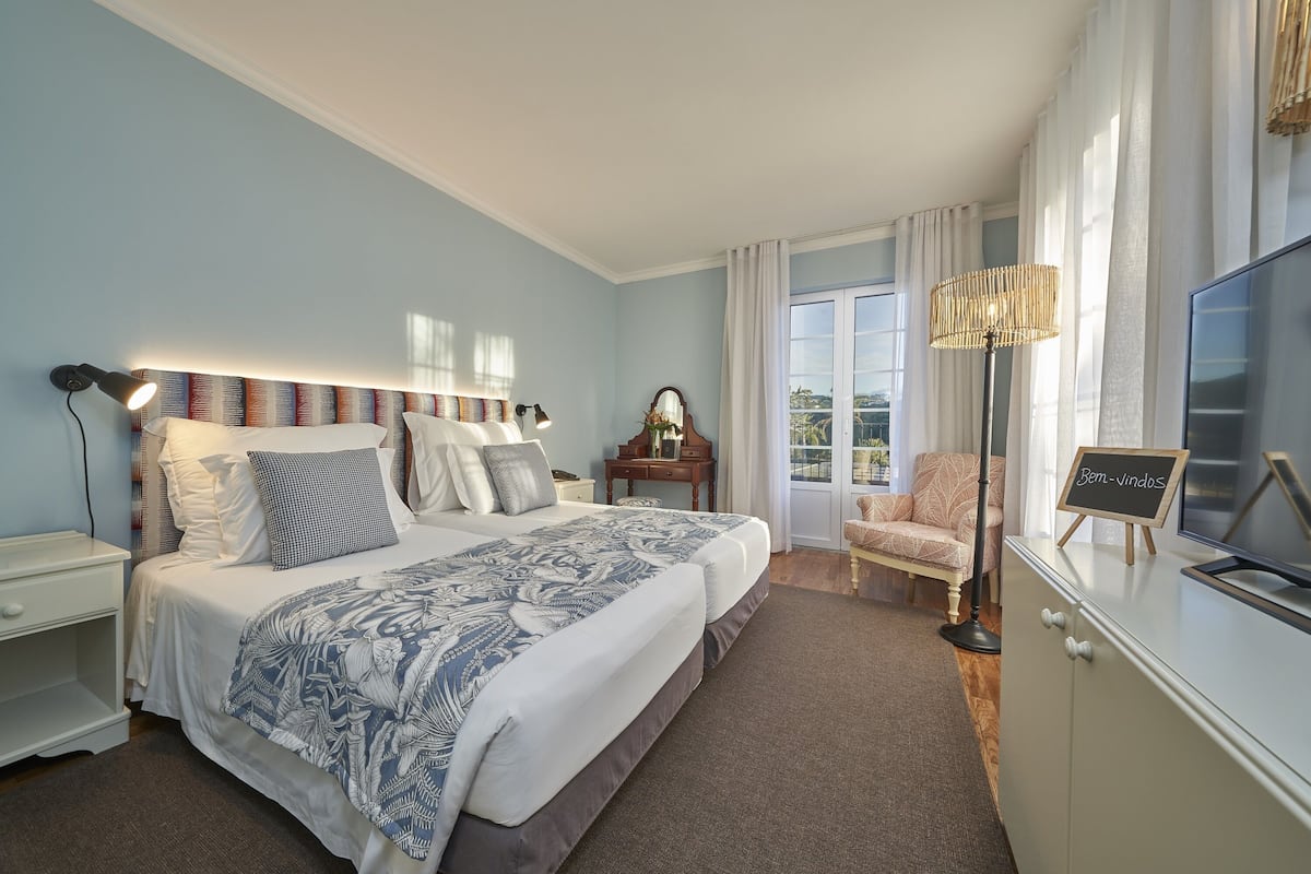 A bedroom with a large bed, a nightstand, a dresser, a chair, and a television.
