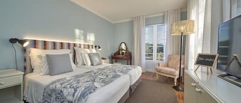 Quarto com uma cama grande, mesa de cabeceira, cômoda, cadeira e televisão.