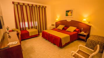 A hotel room with two beds, a desk, a chair, a nightstand, and a window with curtains.