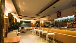 Zona de bar con mostrador, taburetes y una variedad de botellas.