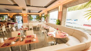 Un comedor moderno con mesas redondas, sillas blancas y un banco acolchado.