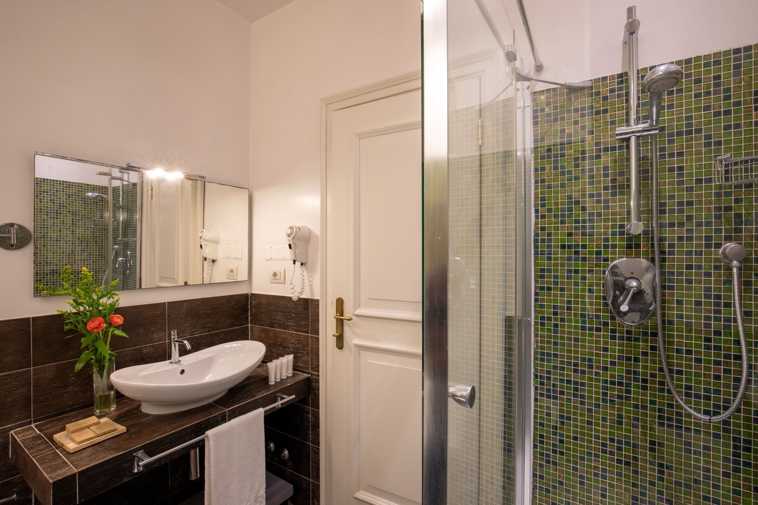 Une salle de bain avec un lavabo blanc, une cabine de douche en verre et un mur carrelé.