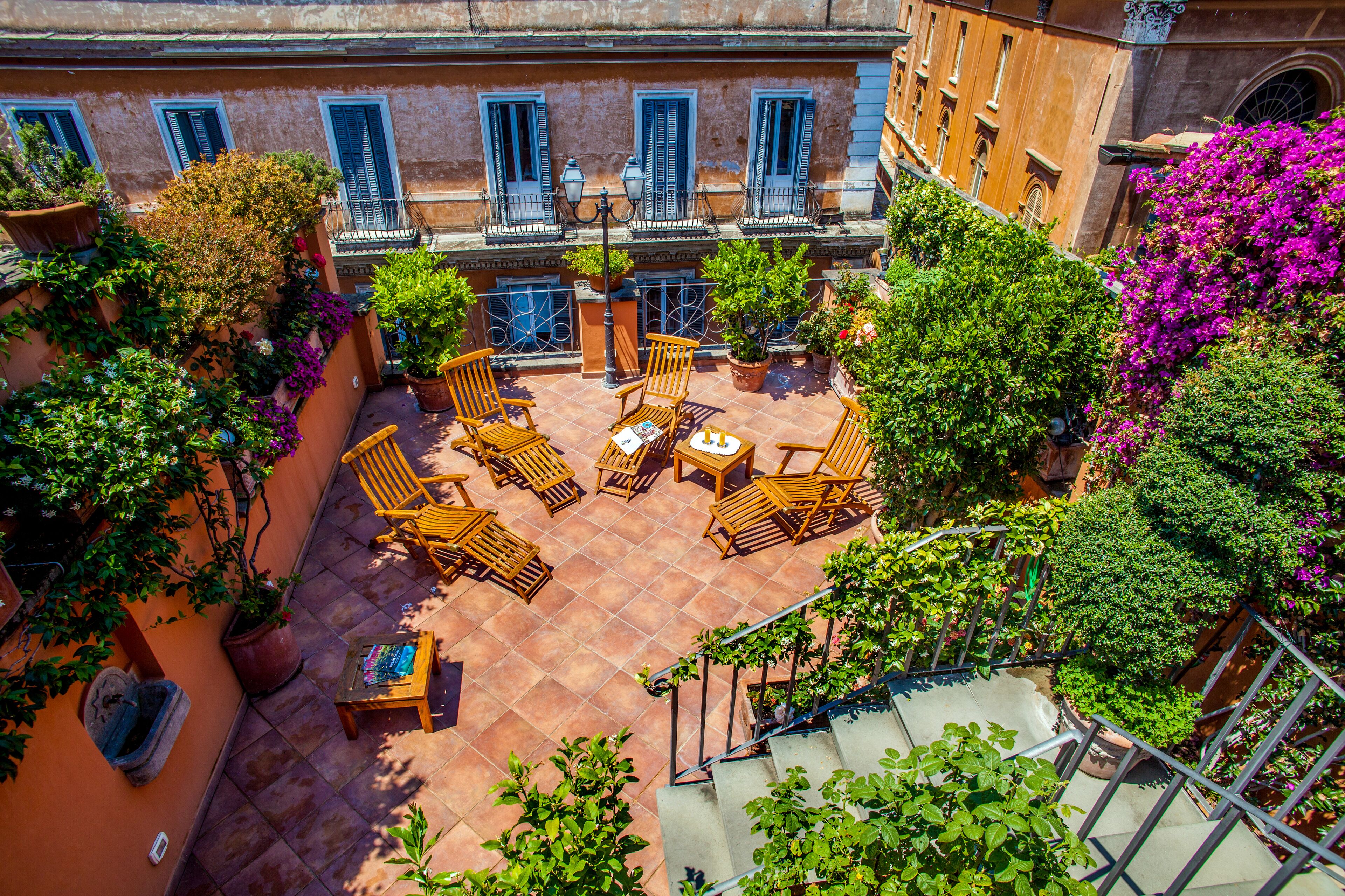 A courtyard with outdoor seating, potted plants, and a staircase.