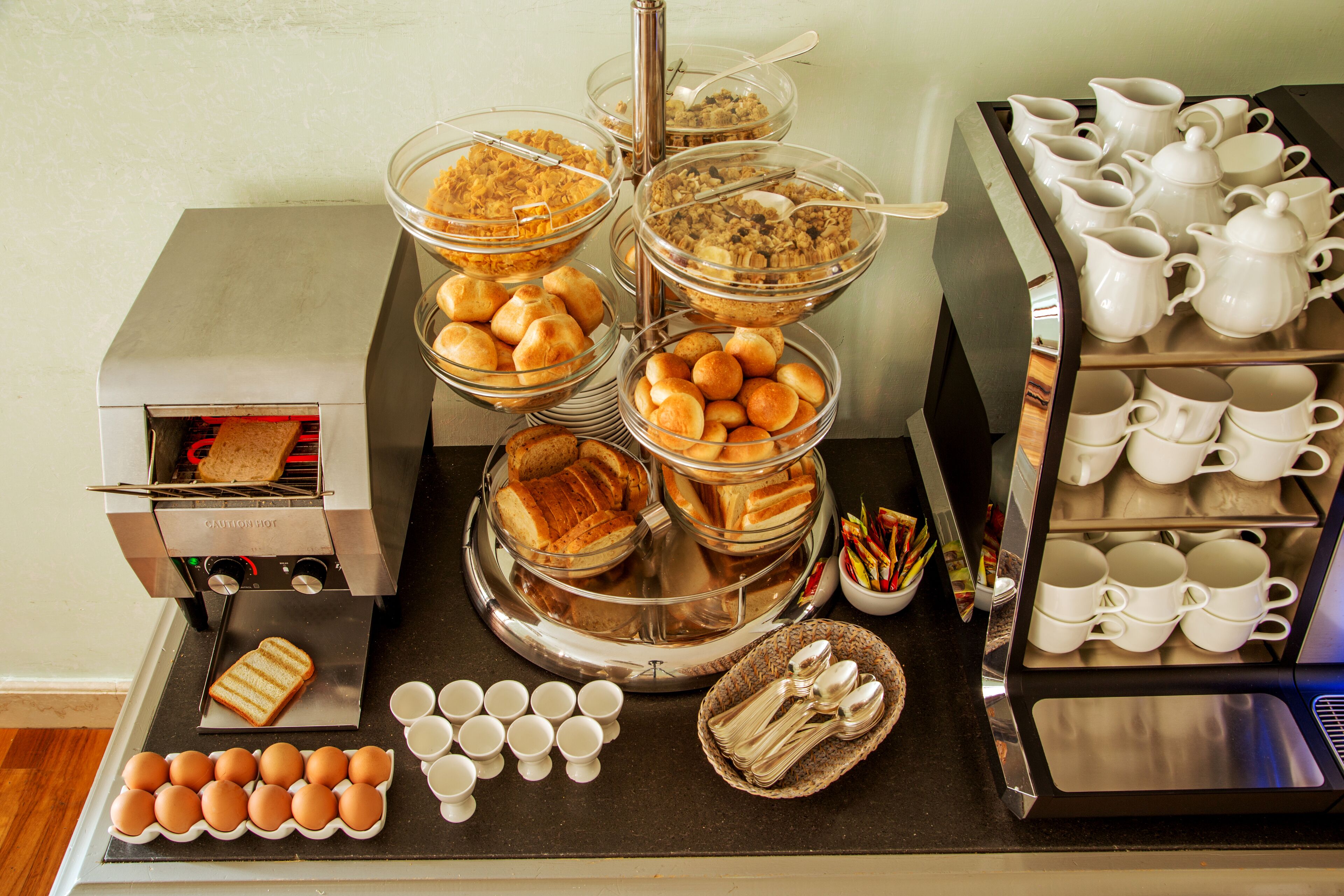 A buffet setup with various food items, including bread, pastries, and beverages.