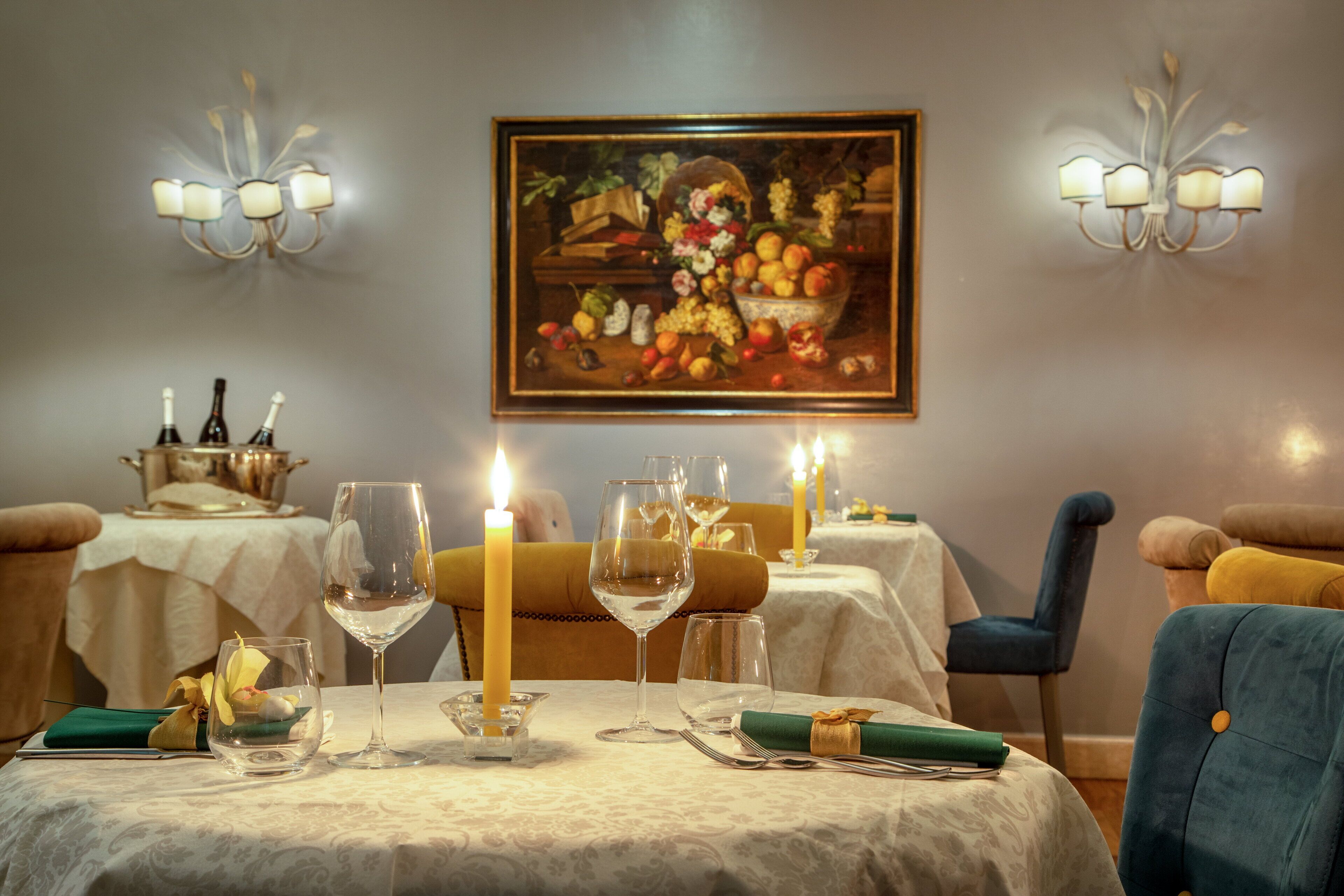 A dining table set with wine glasses, a candle, and a fruit basket.