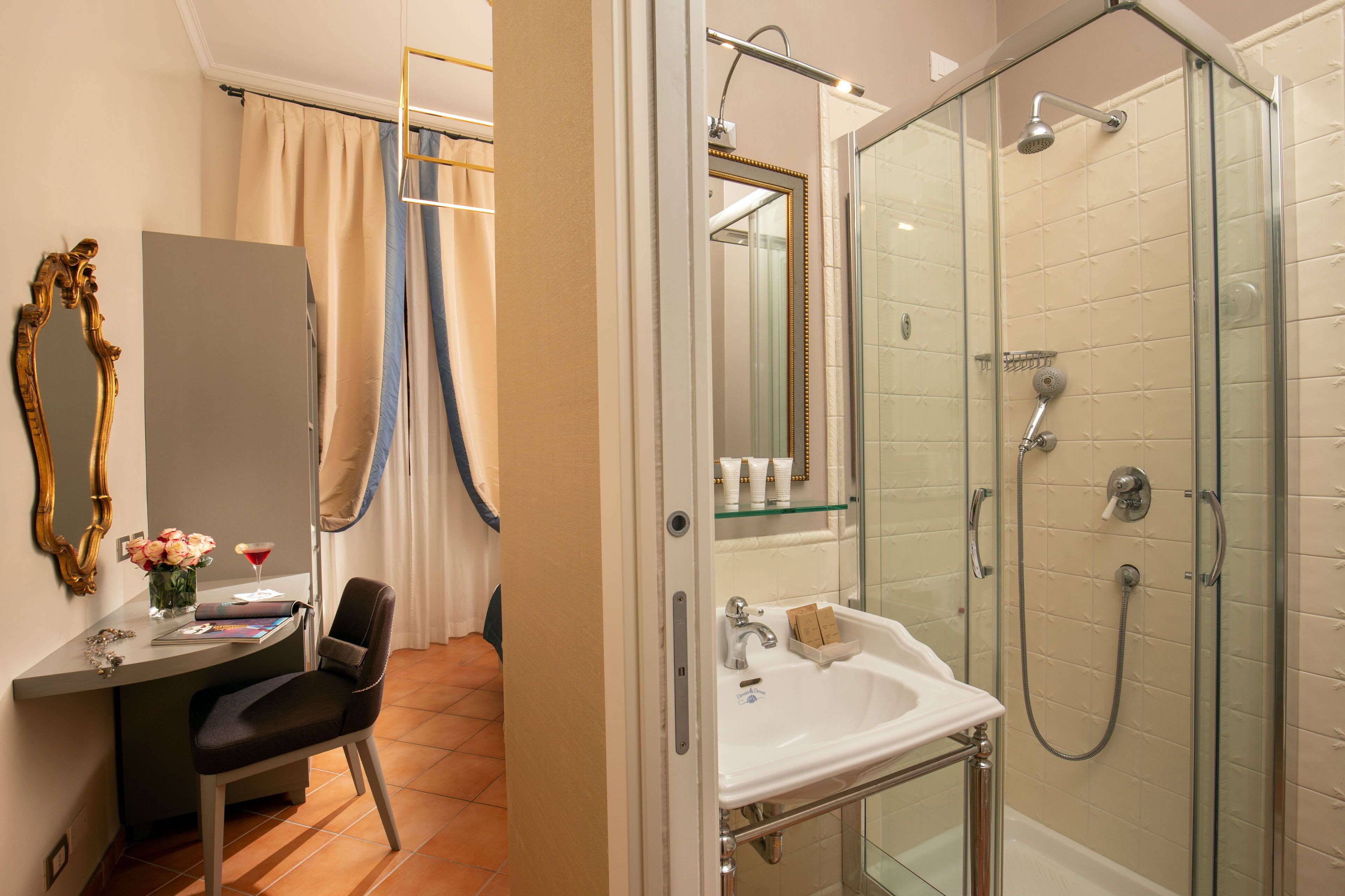 A bathroom with a glass-enclosed shower, a vanity with a sink, and a chair.