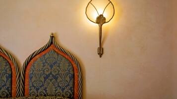 Una cama con un cabecero decorado y una lámpara fijada a la pared.