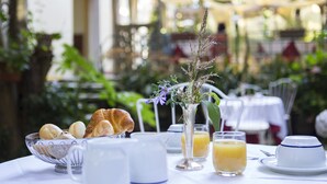 Ett frukostbord med croissanter, en vas med blommor och glas med apelsinjuice.