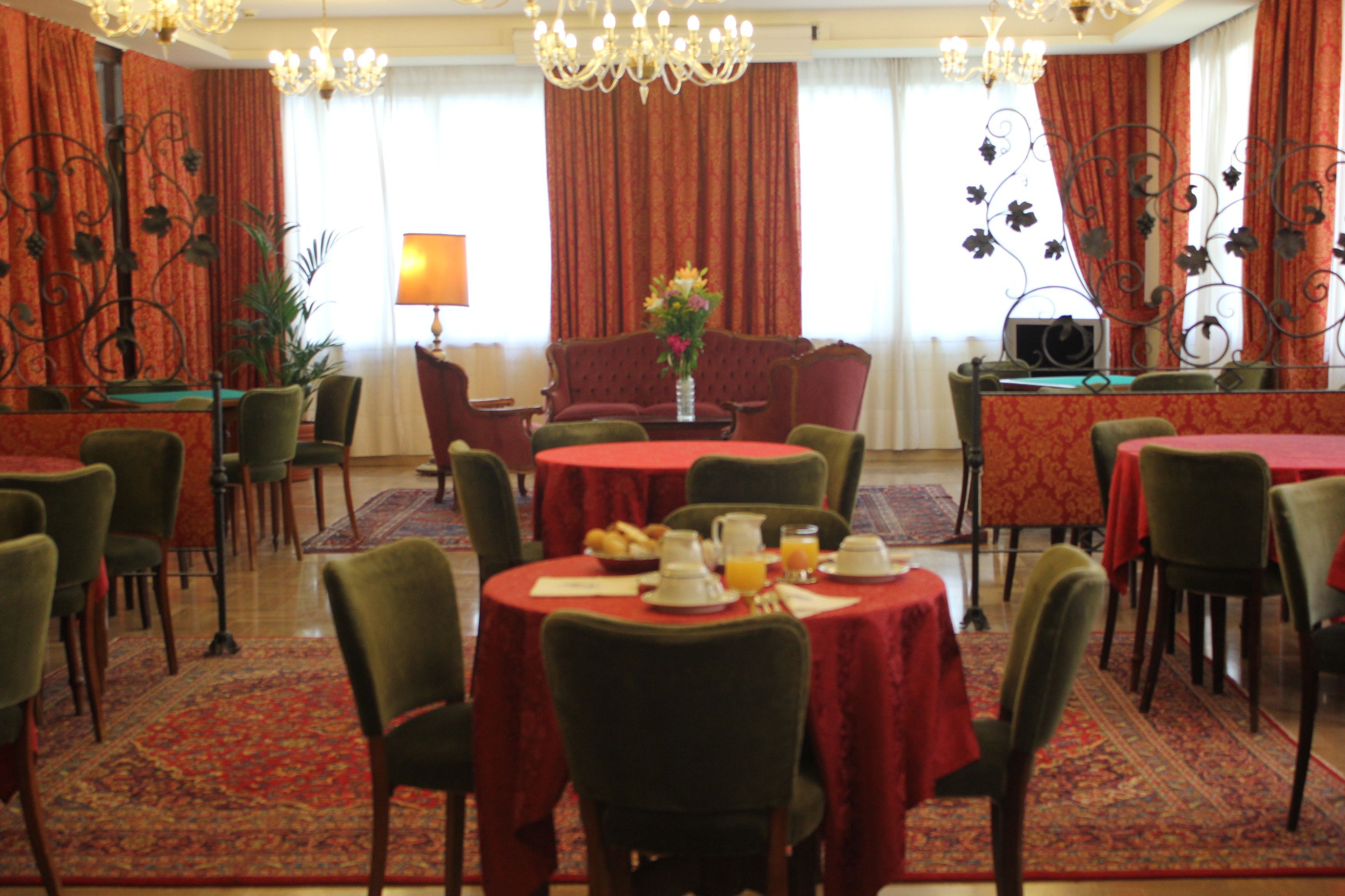 A dining area with round tables, chairs, and a chandelier.