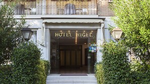 Ingången till Hotel Rigel är tydligt markerad med en skylt, och det finns trappsteg som leder upp till entrén. Dessutom finns det en balkong med utomhusmöbler.