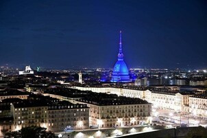 A cityscape at night with a prominent illuminated tower in the center.