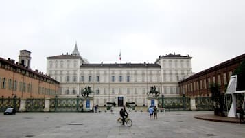 Un gran edificio histórico con arquitectura clásica, un patio central y estatuas.