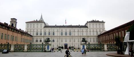 Un gran edificio histórico con arquitectura clásica, un patio central y estatuas.