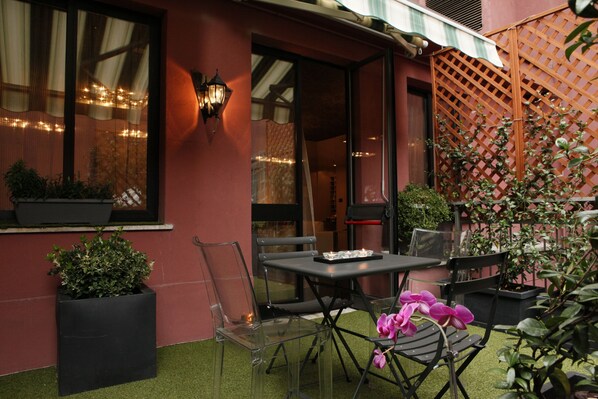 An outdoor patio with a table and chairs, potted plants, and a lattice fence. - Hotel Lancaster (Turin)