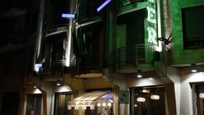 Un hotel llamado "Lancaster" con un letrero llamativo, varios balcones y una entrada bien iluminada.