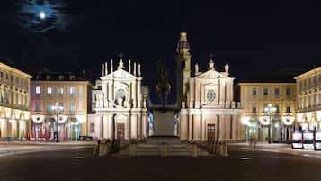 A square with a central monument, surrounded by classical buildings with illuminated facades.