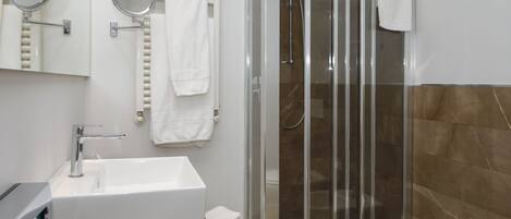 A modern bathroom with a glass-enclosed shower, a white sink, and two wall-mounted mirrors.