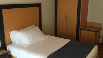 Ein Hotelzimmer mit Bett, Schrank und kleinem Tisch.
