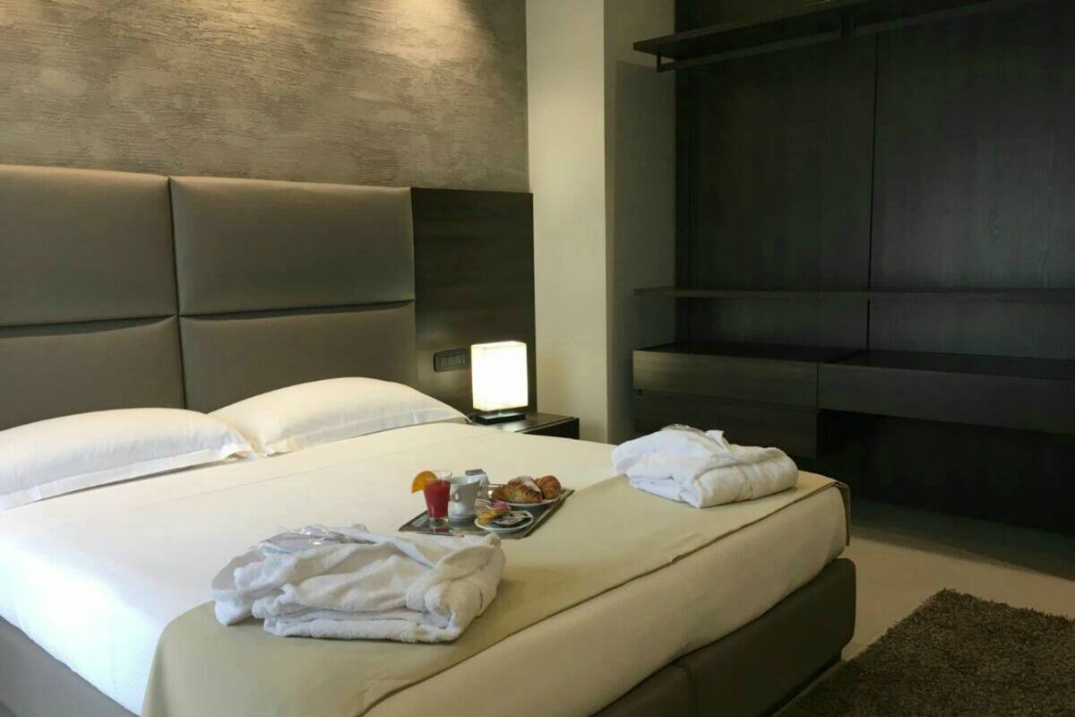 A modern hotel room with a large bed, a flat-screen TV, and a bedside table with a lamp.