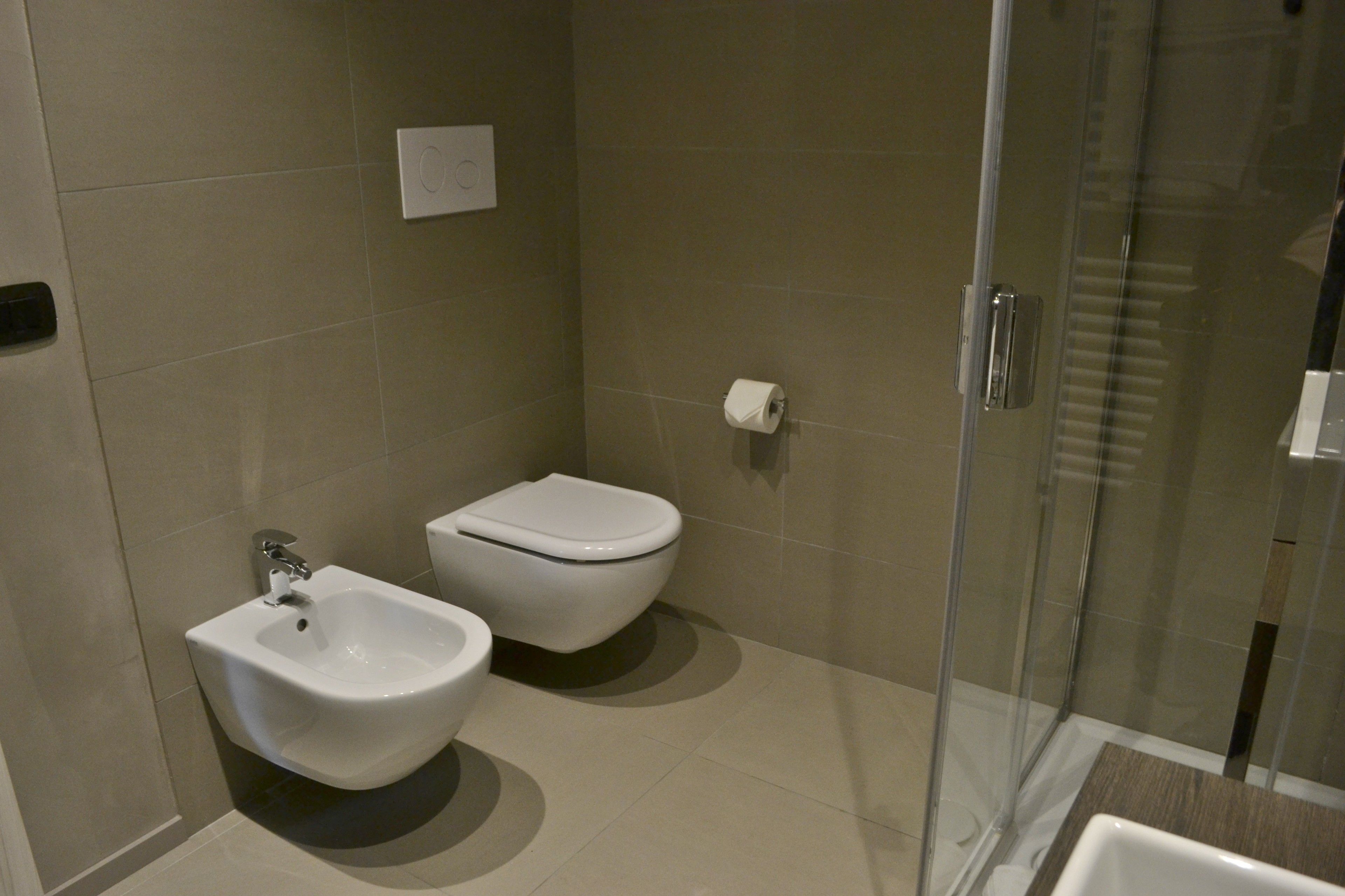 A modern bathroom with a bidet, toilet, and glass shower enclosure.