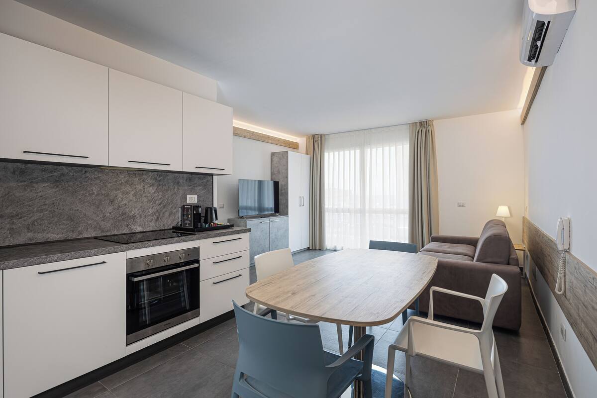 Una cocina moderna con horno empotrado y comedor con mesa y sillas de madera.