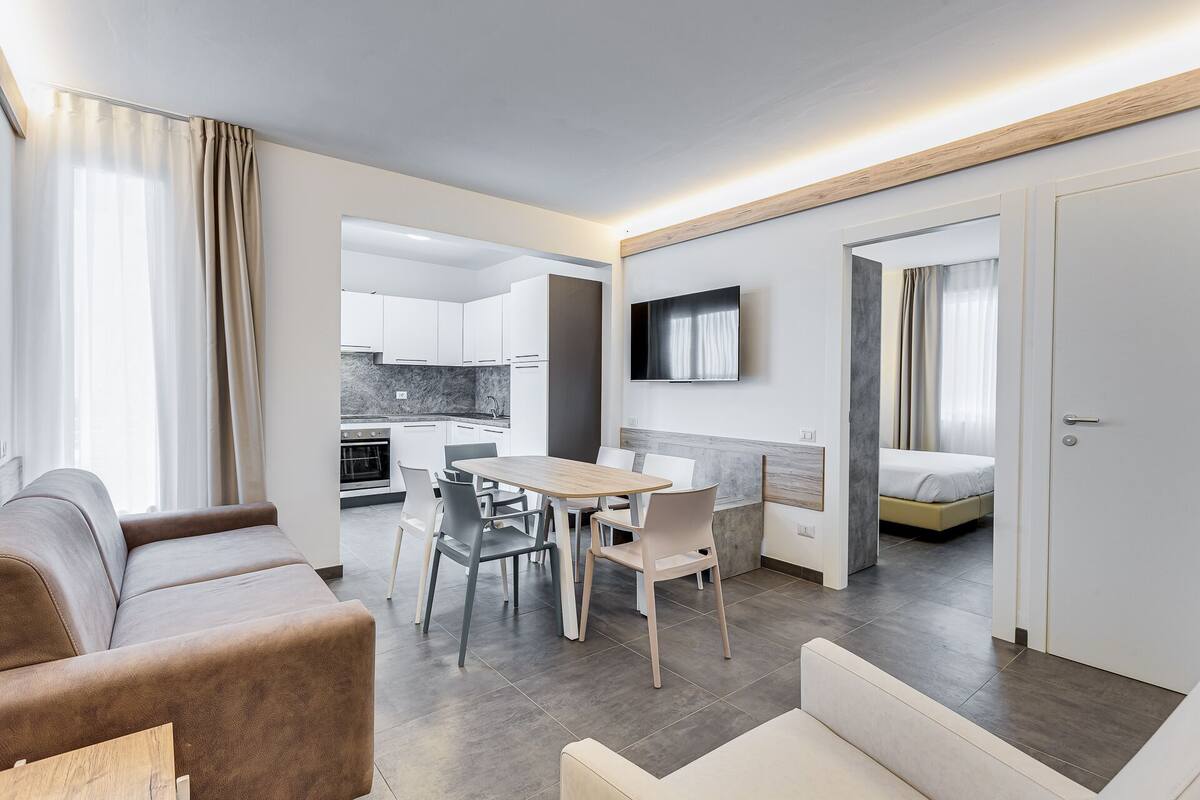 Una habitación de hotel moderna con comedor, sofá, televisión y cama.