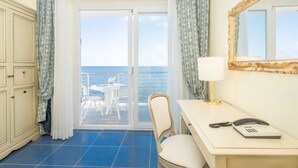 Una habitación de hotel con balcón, un escritorio con teléfono y una silla.