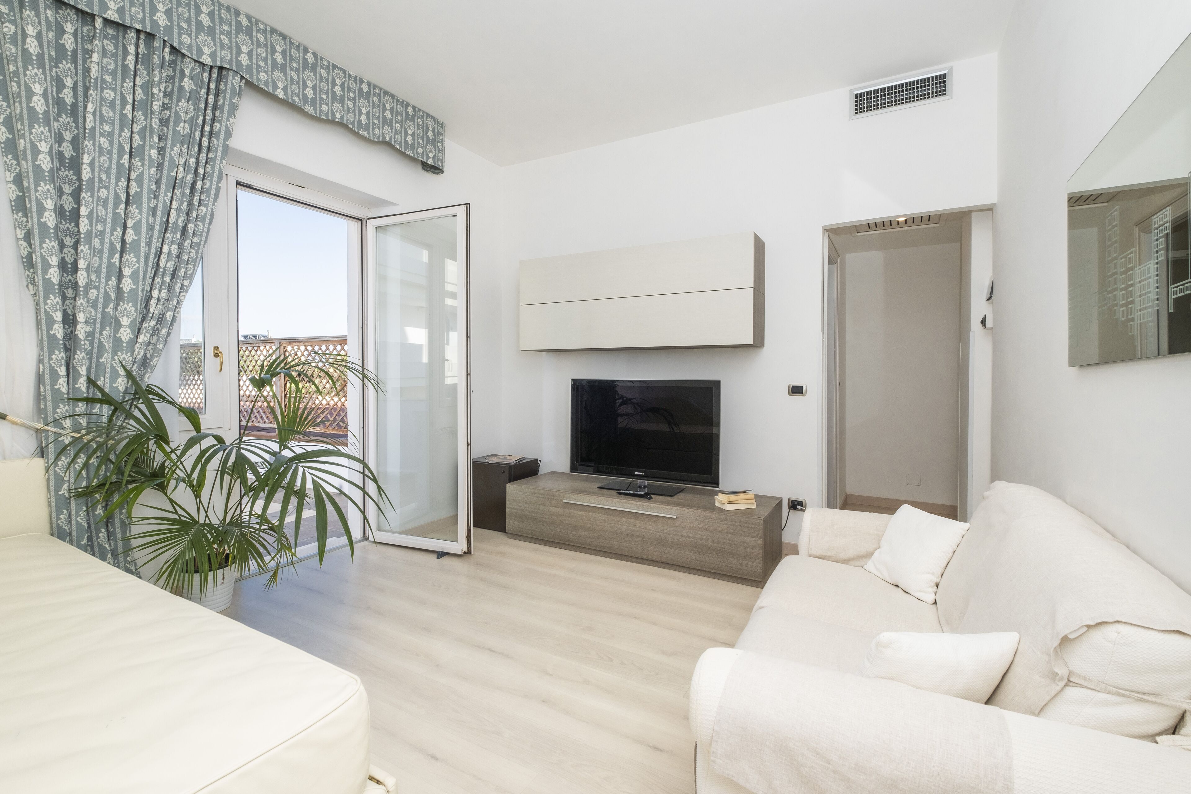 Una sala de estar moderna con un sofá, una televisión y una planta en maceta.