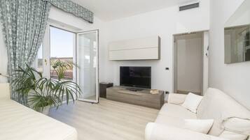Una sala de estar moderna con un sofá, una televisión y una planta en maceta.
